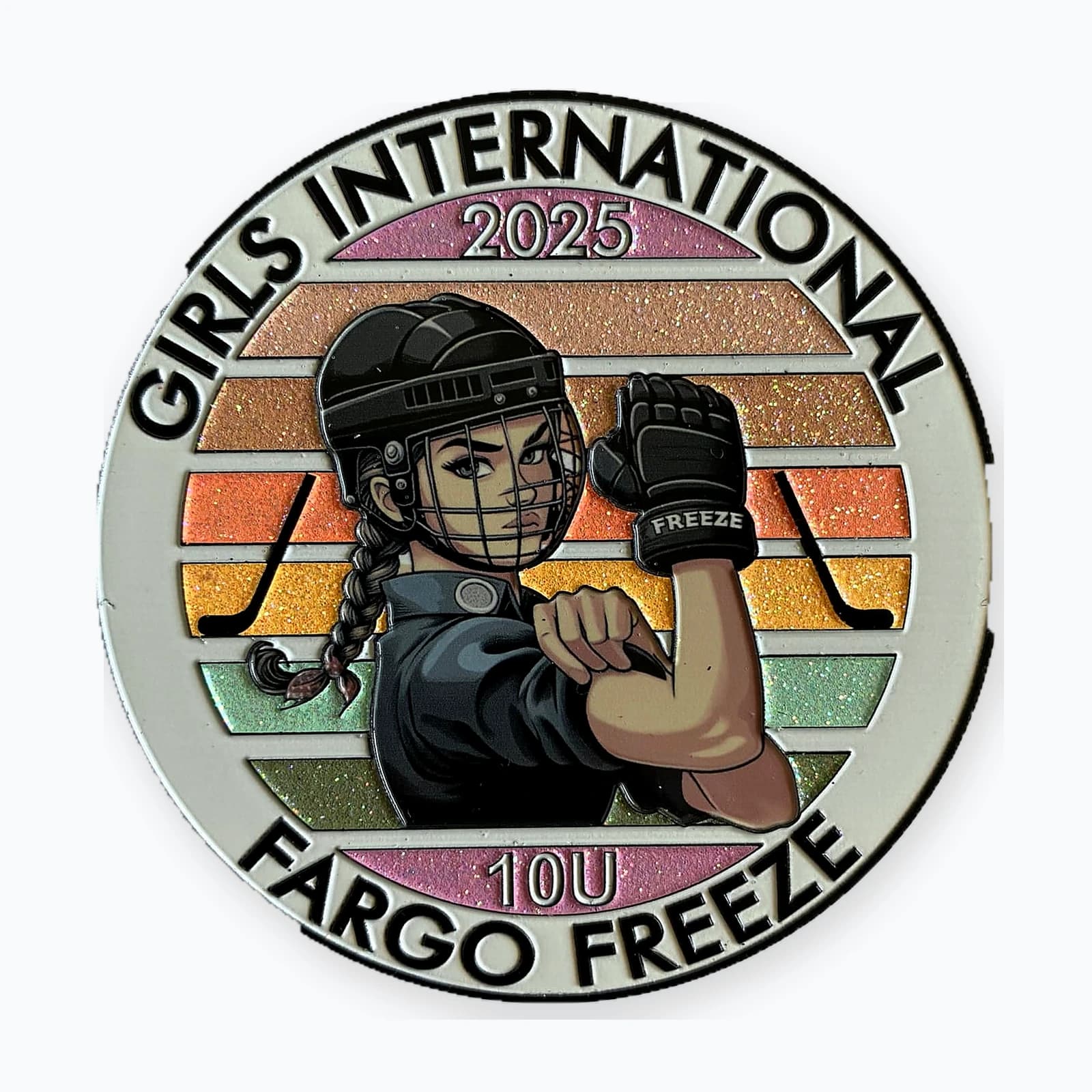 A round Girls International trading pin for a Fargo Freeze team, showing a girl player flexing against a striped glitter background